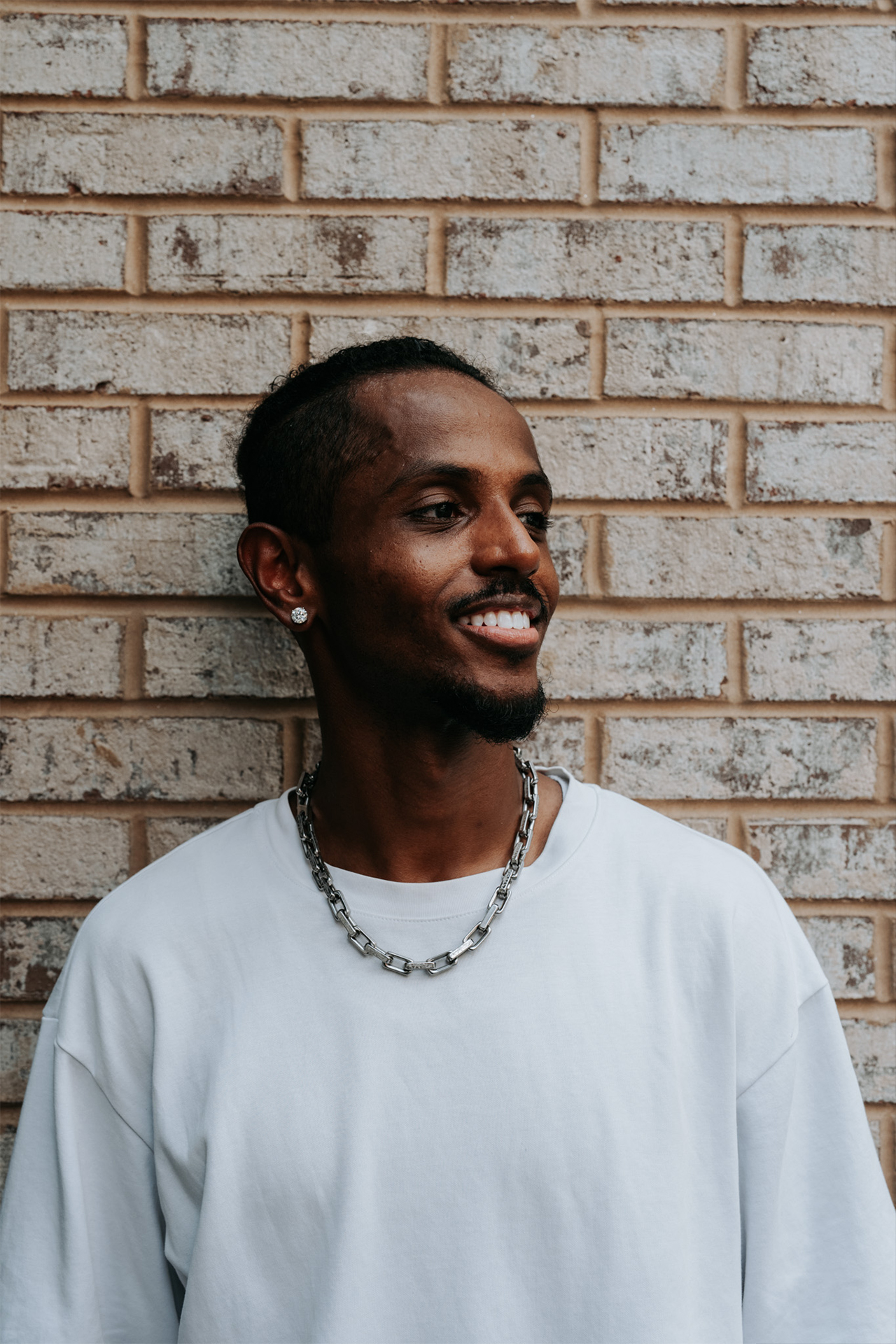 Meni close portrait smiling against a brick wall, Crystal City, July 2026.