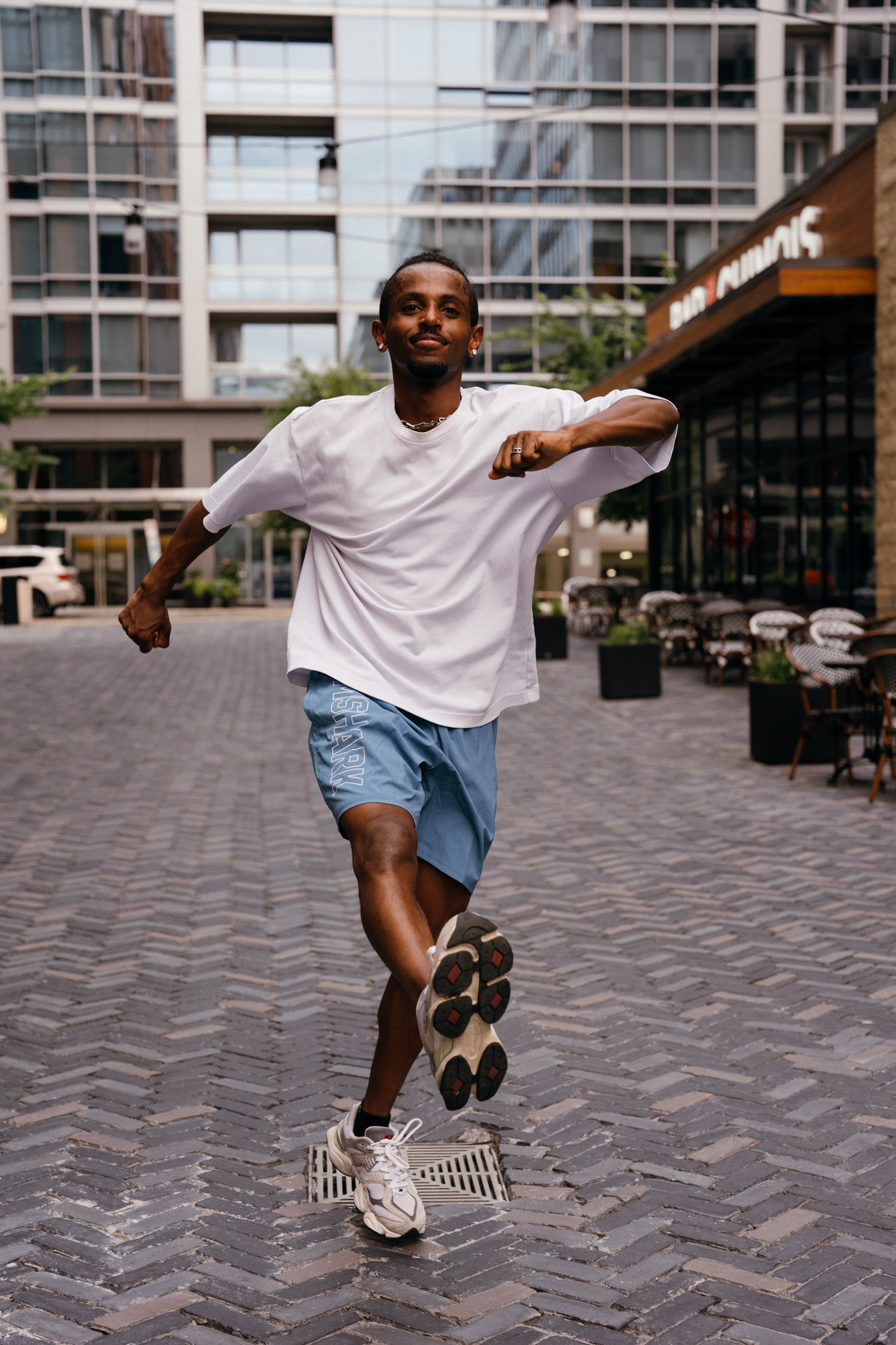 Meni mid-dance run, full smile, energetic movement, Crystal City courtyard, July 2026.