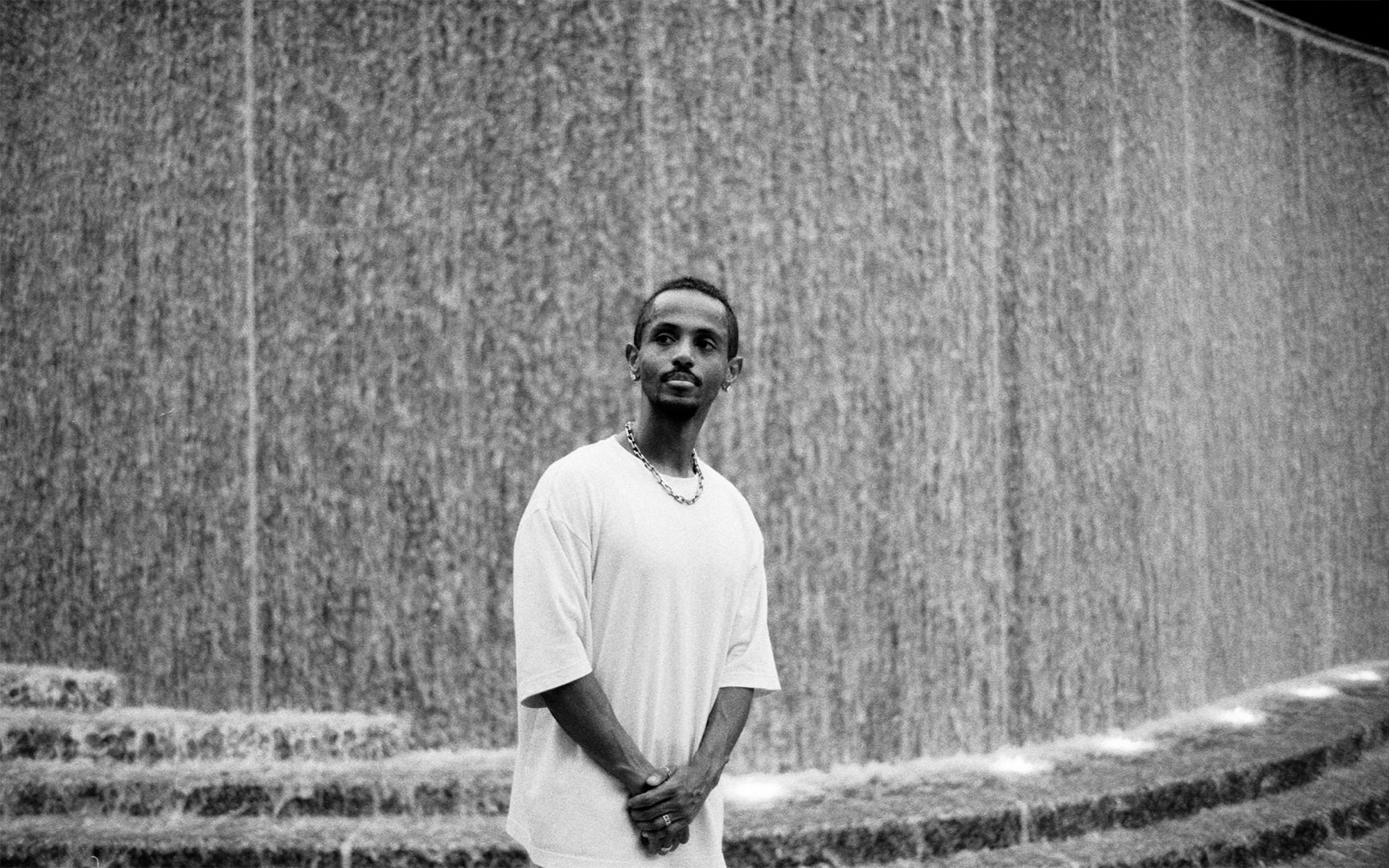 Meni standing in front of a waterfall wall at a DC street photographer meetup, July 2026.