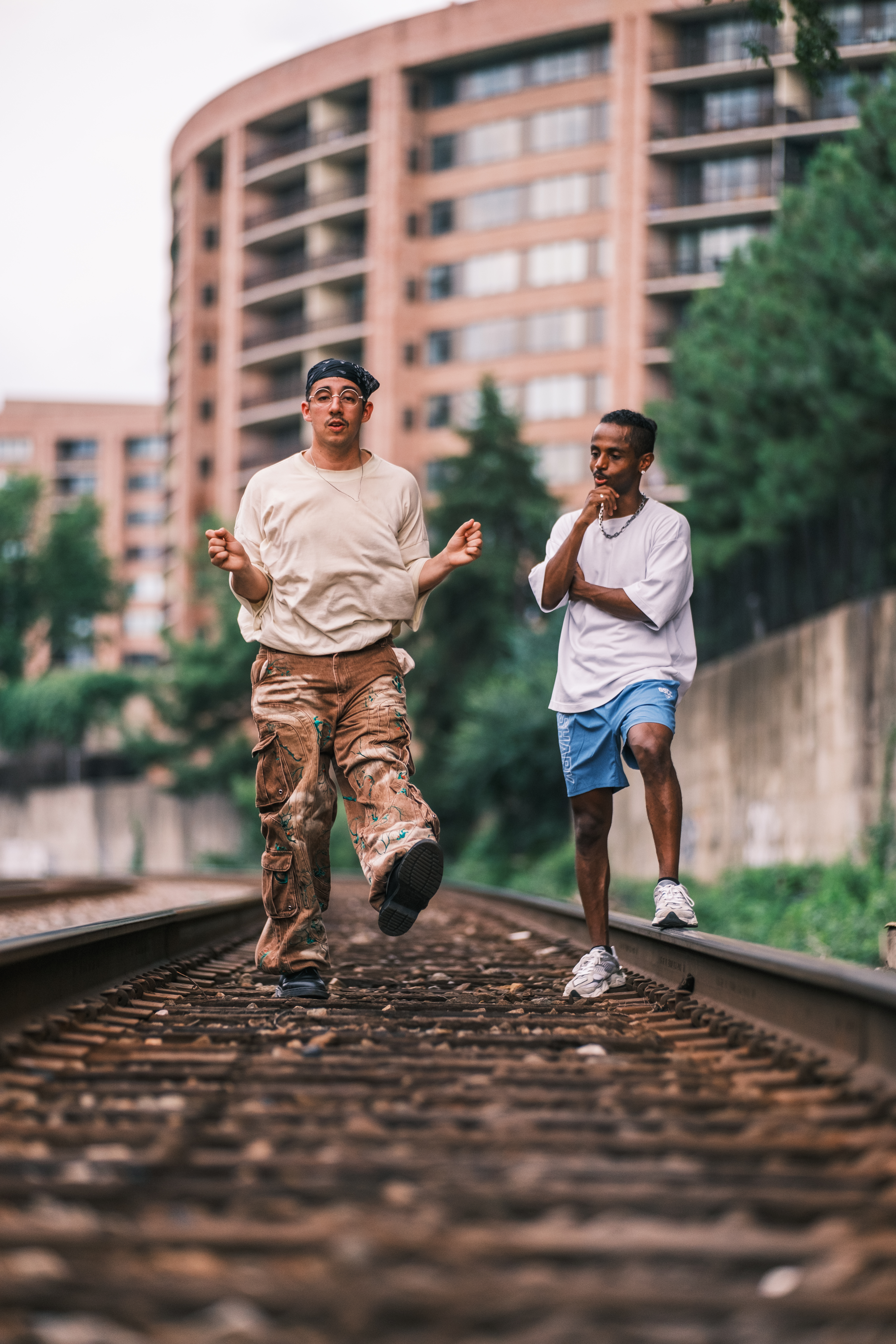 Meni teaching dancer Inca the Beat Ya Feet style on the railway tracks at a DC street photographer meetup, July 2026.